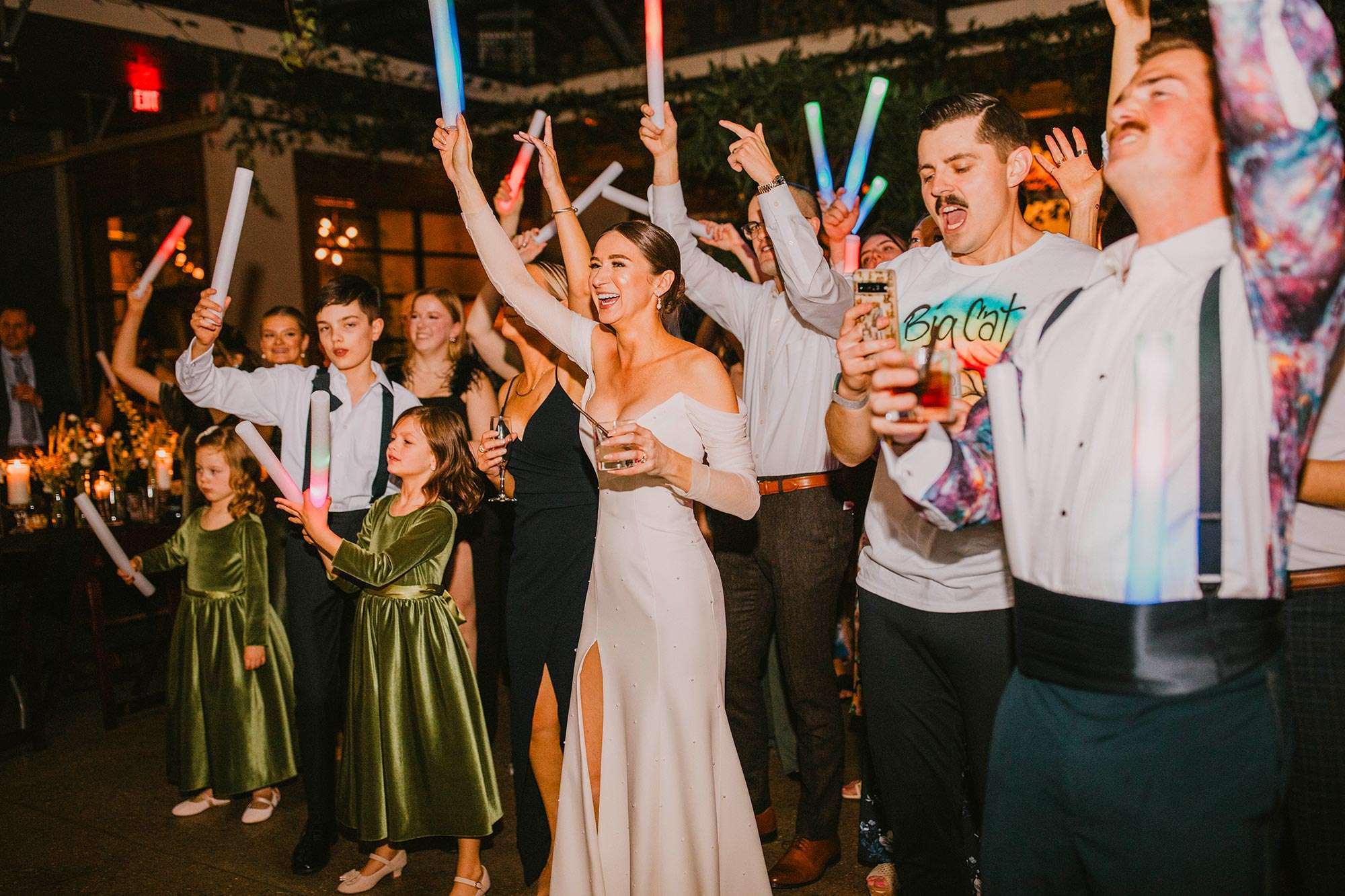 bride and groom dancing with guests holding light sticks in air bride and groom dancing with guests holding light sticks in air