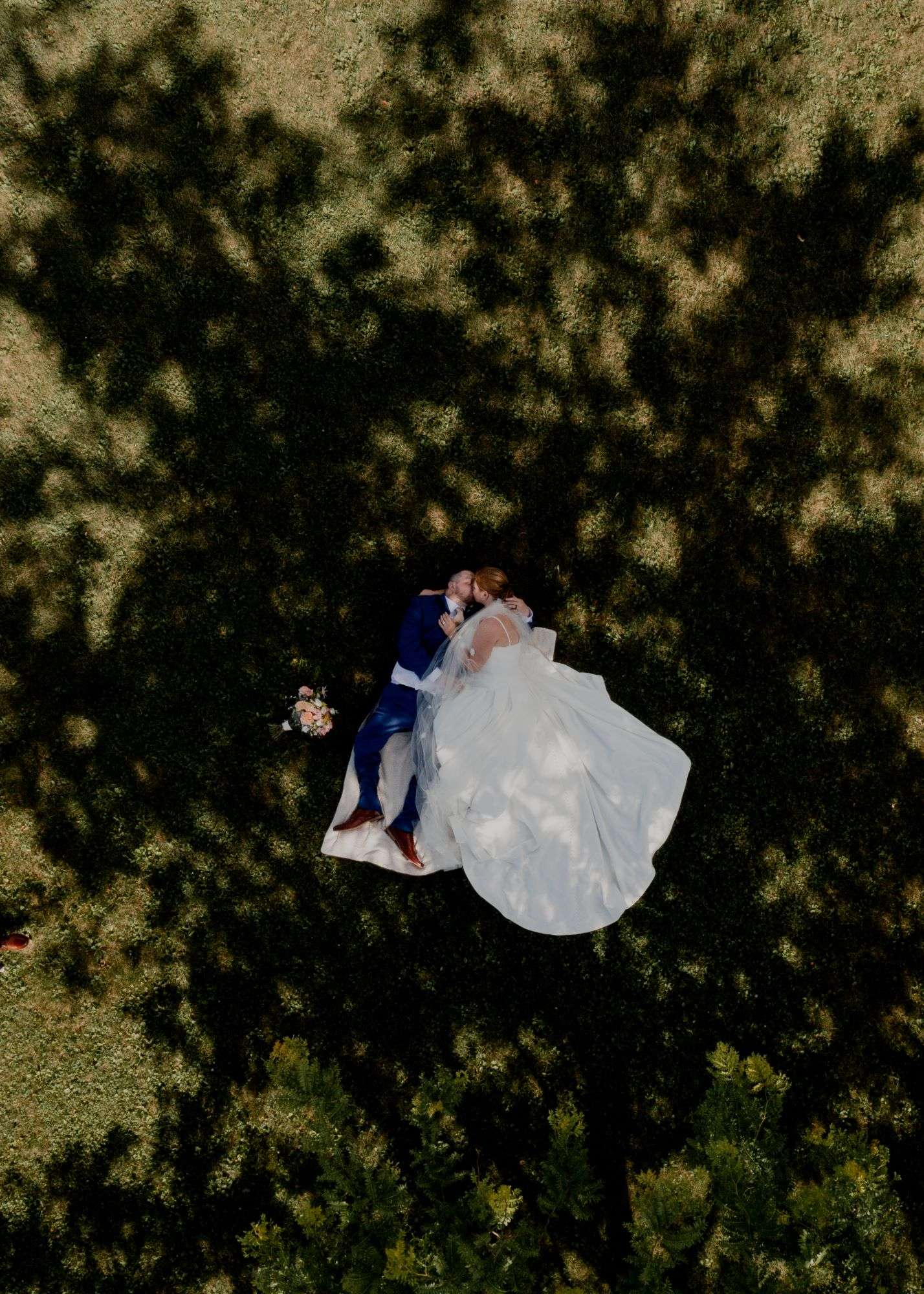 Bride and groom laying in field as drone photo takes shot of them from above. Bride and groom laying in field as drone photo takes shot of them from above.