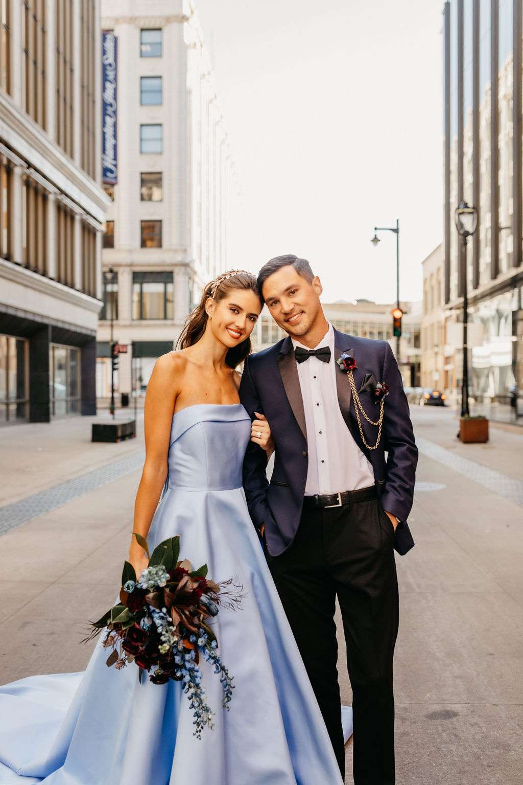 Bride in light blue wedding dress holding moody wedding bouquet with groom in navy suit and unique boutonniere. Bride in light blue wedding dress holding moody wedding bouquet with groom in navy suit and unique boutonniere.
