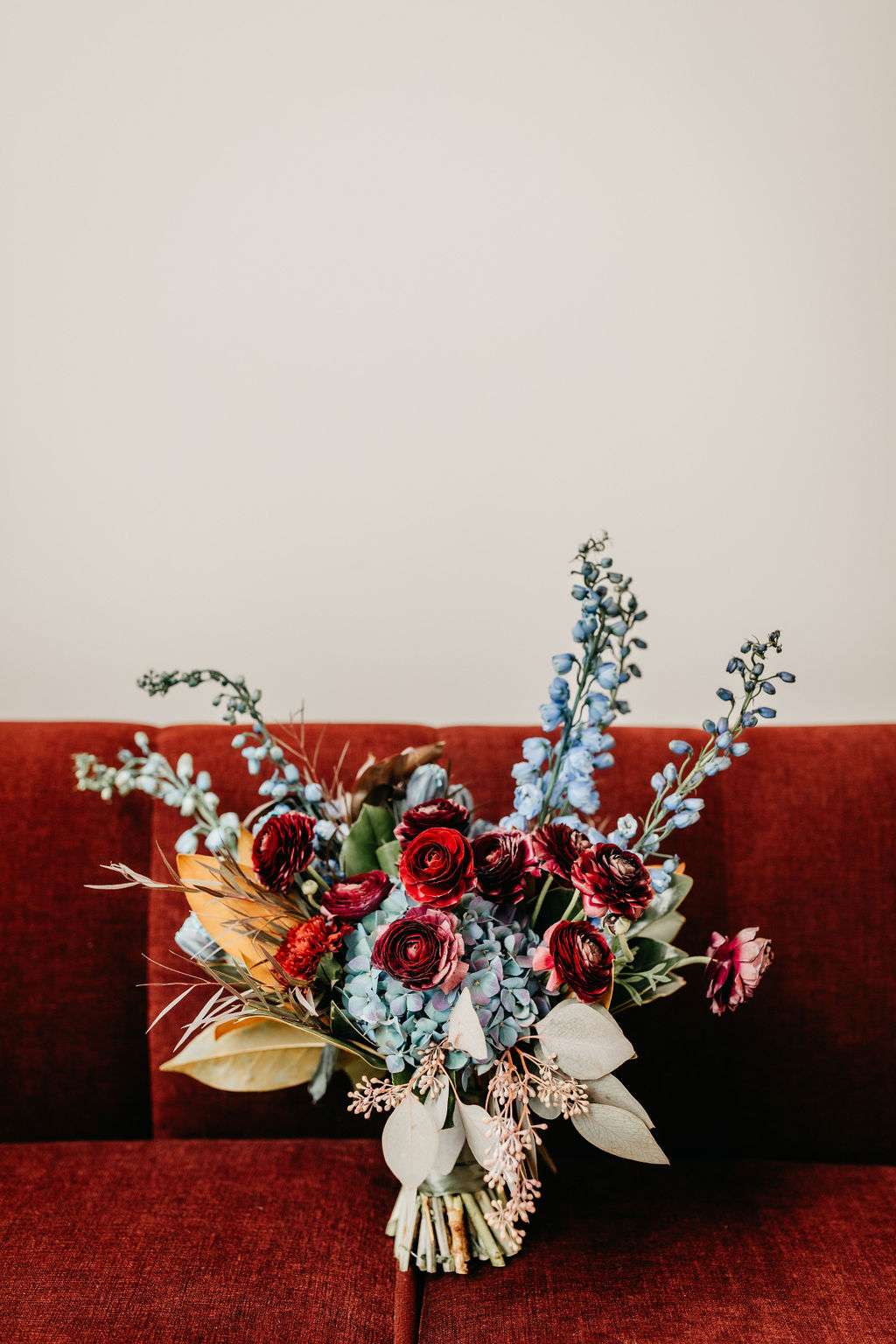 Moody wedding bouquet featuring burgundy, blue and orange flowers by Belle Fiori. Moody wedding bouquet featuring burgundy, blue and orange flowers by Belle Fiori.