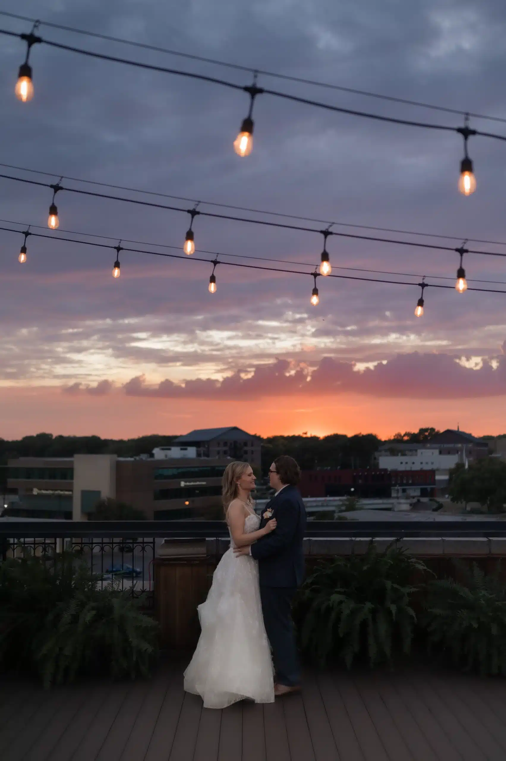 Bride and groom dancing under the cafe lights on the rooftop of Hotel GOodwin.