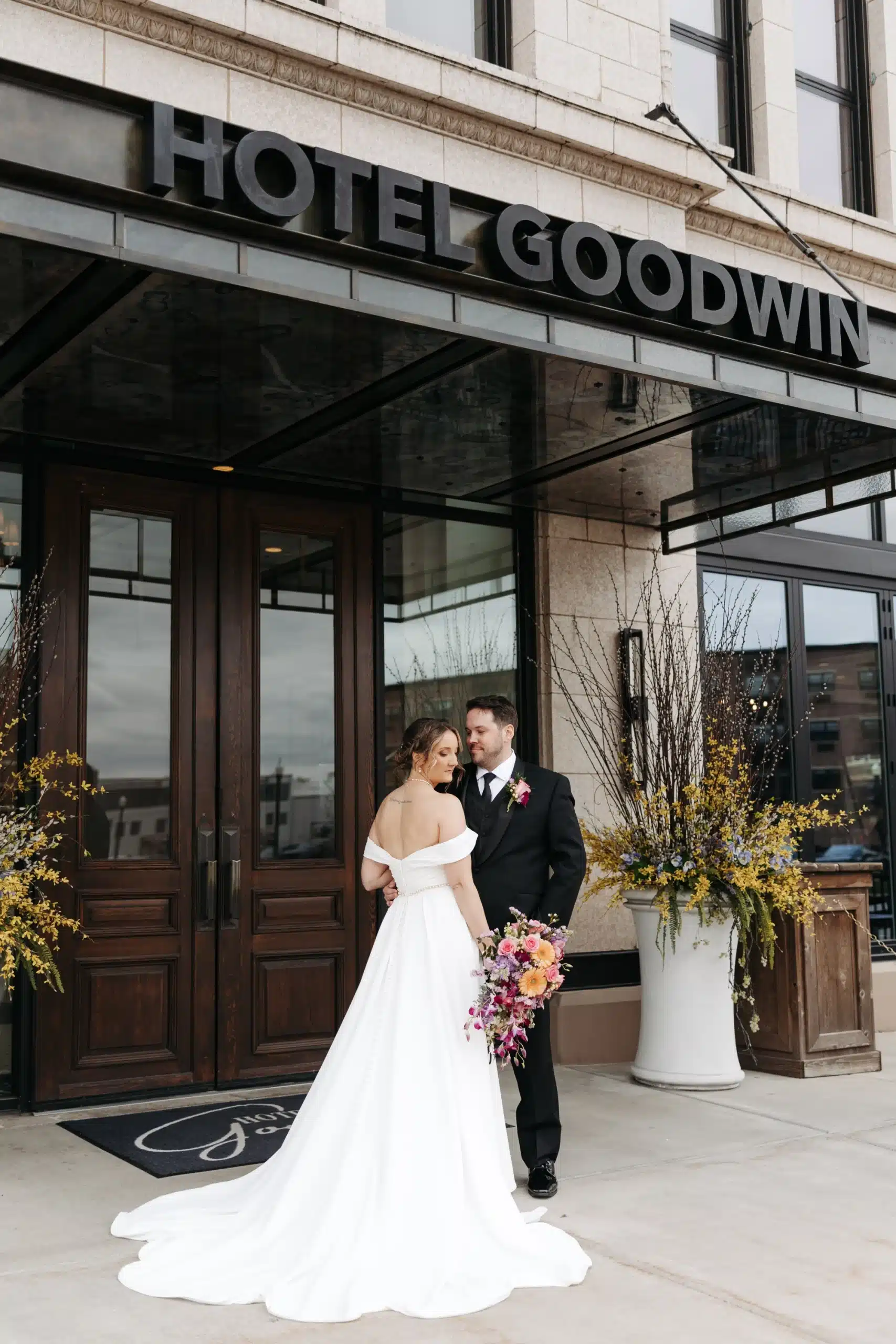 Bride and groom pose under the awning of Hotel Goodwin.