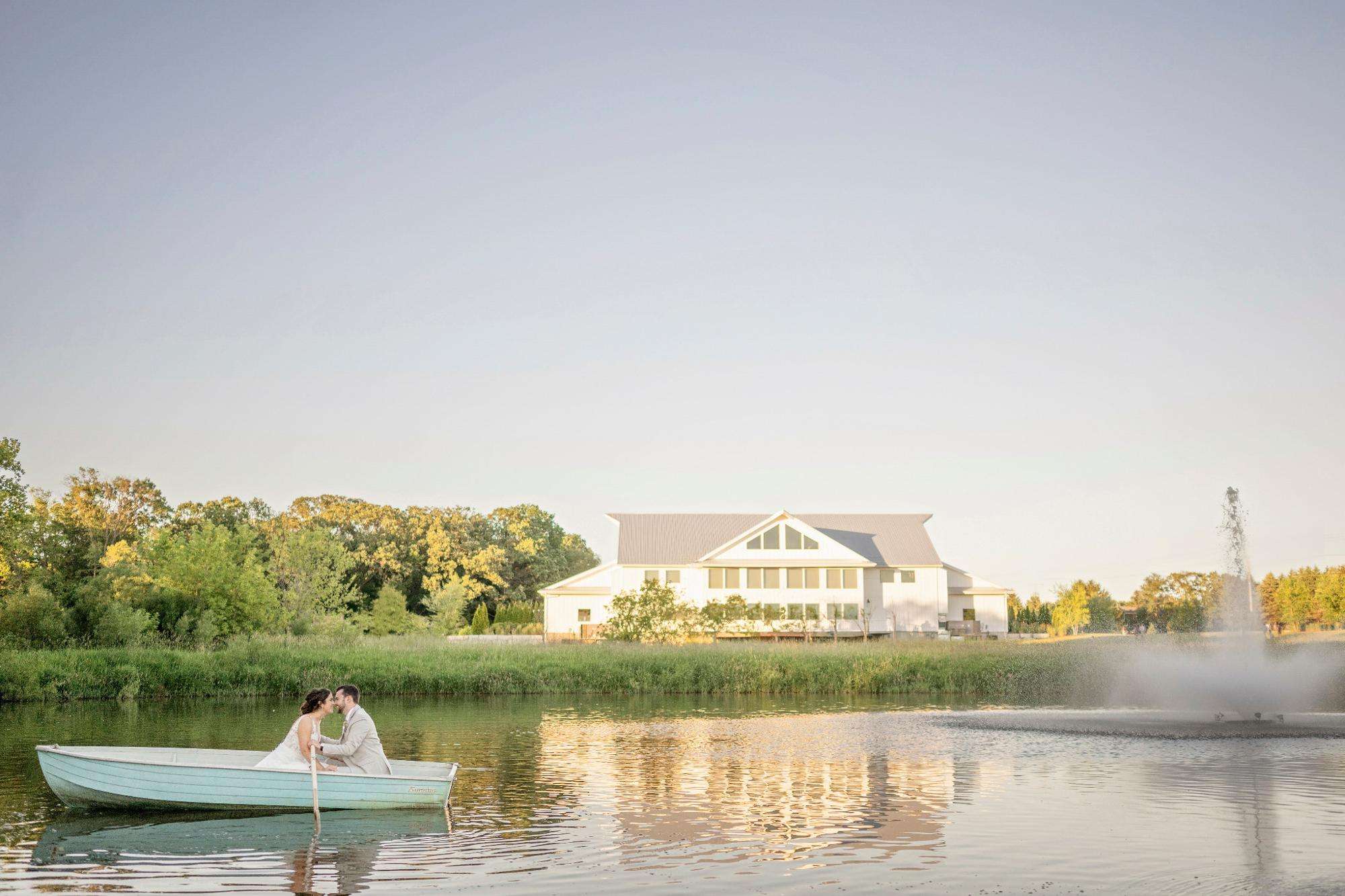 romantic rowboat kiss on a peaceful pond near a modern white barn, by Allysha Noelle Photography.