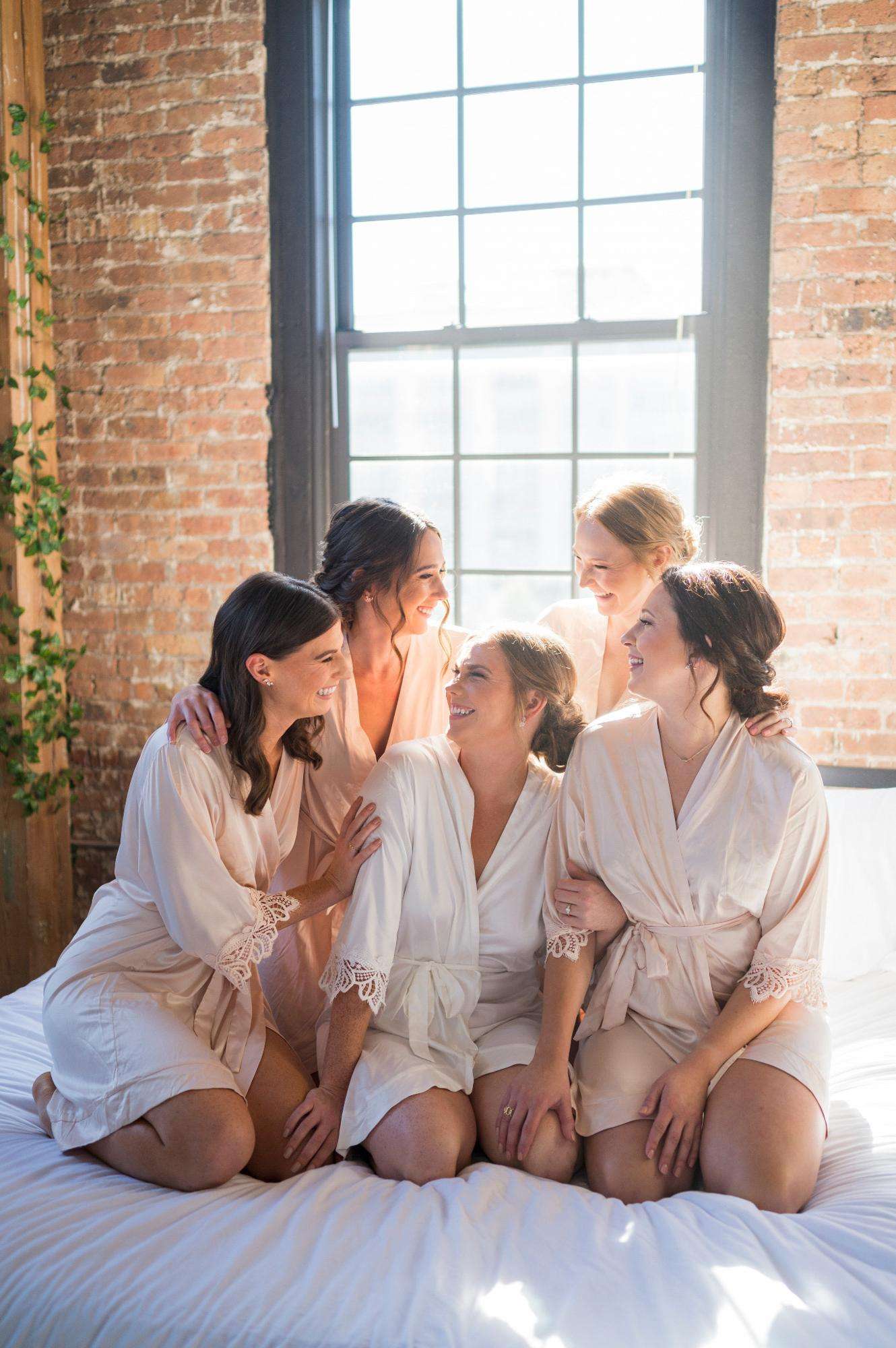 Bridesmaids share laughter and light in a cozy loft setting, beautifully captured by Allysha Noelle Photography.