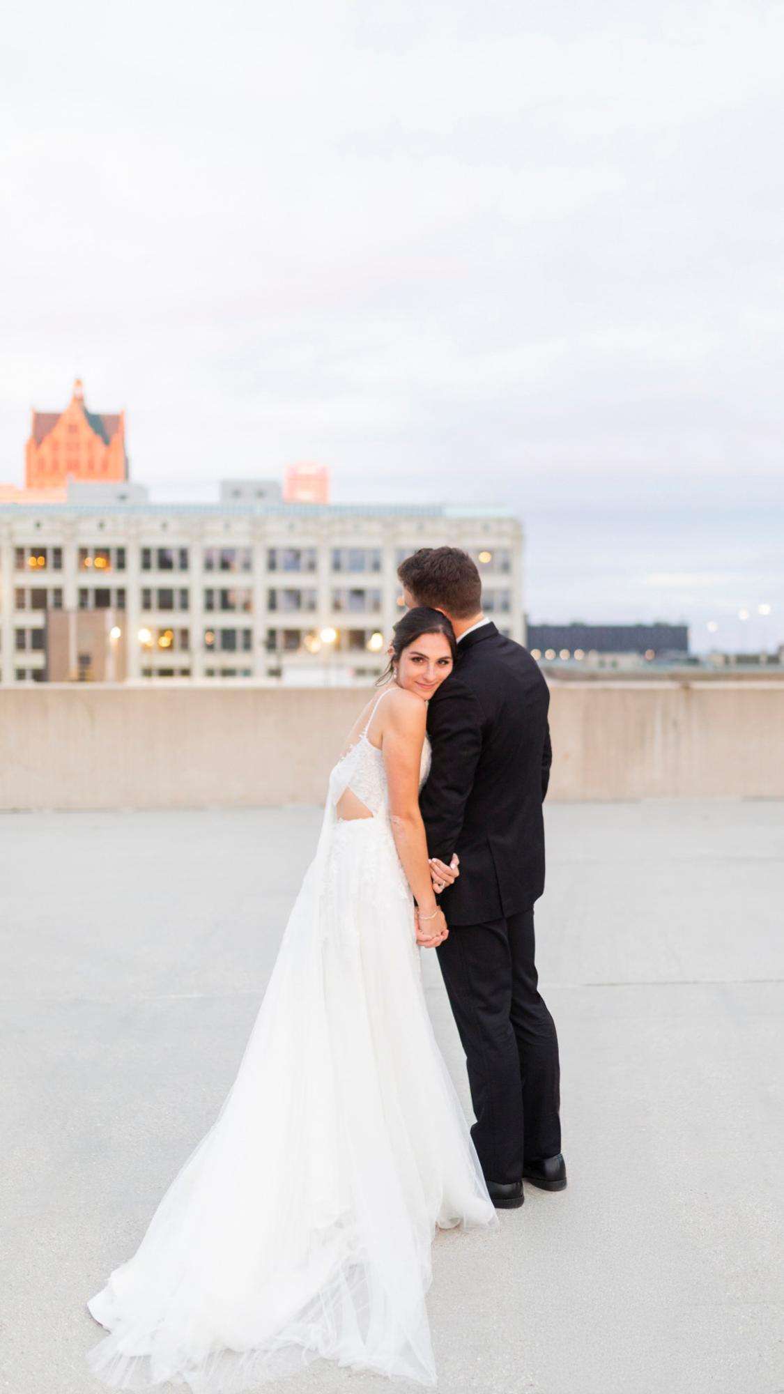 A rooftop embrace with a glowing city skyline backdrop, by Allysha Noelle Photography.