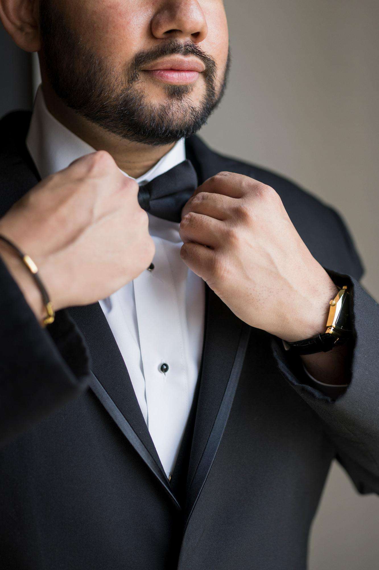 A groom adjusts his bow tie in a quiet, elegant moment, expertly captured by Allysha Noelle Photography.
