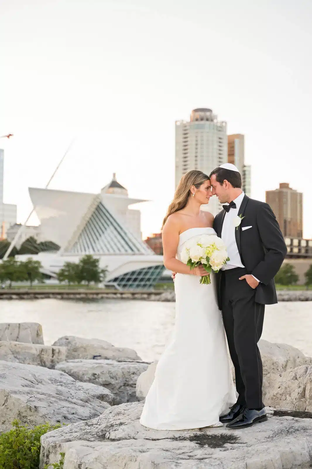 Bride and groom forehead to forehead in front of the Milwaukee Art Museum.