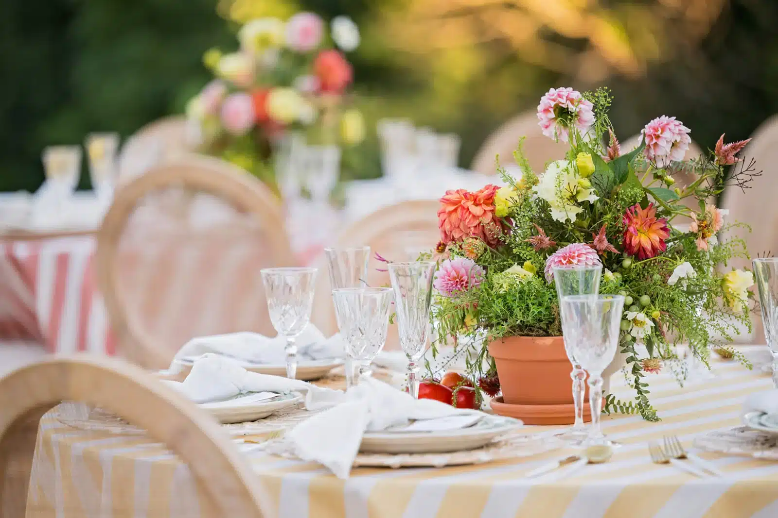Table decor, yellow and white striped tablecloth with colorful floral centerpiece.