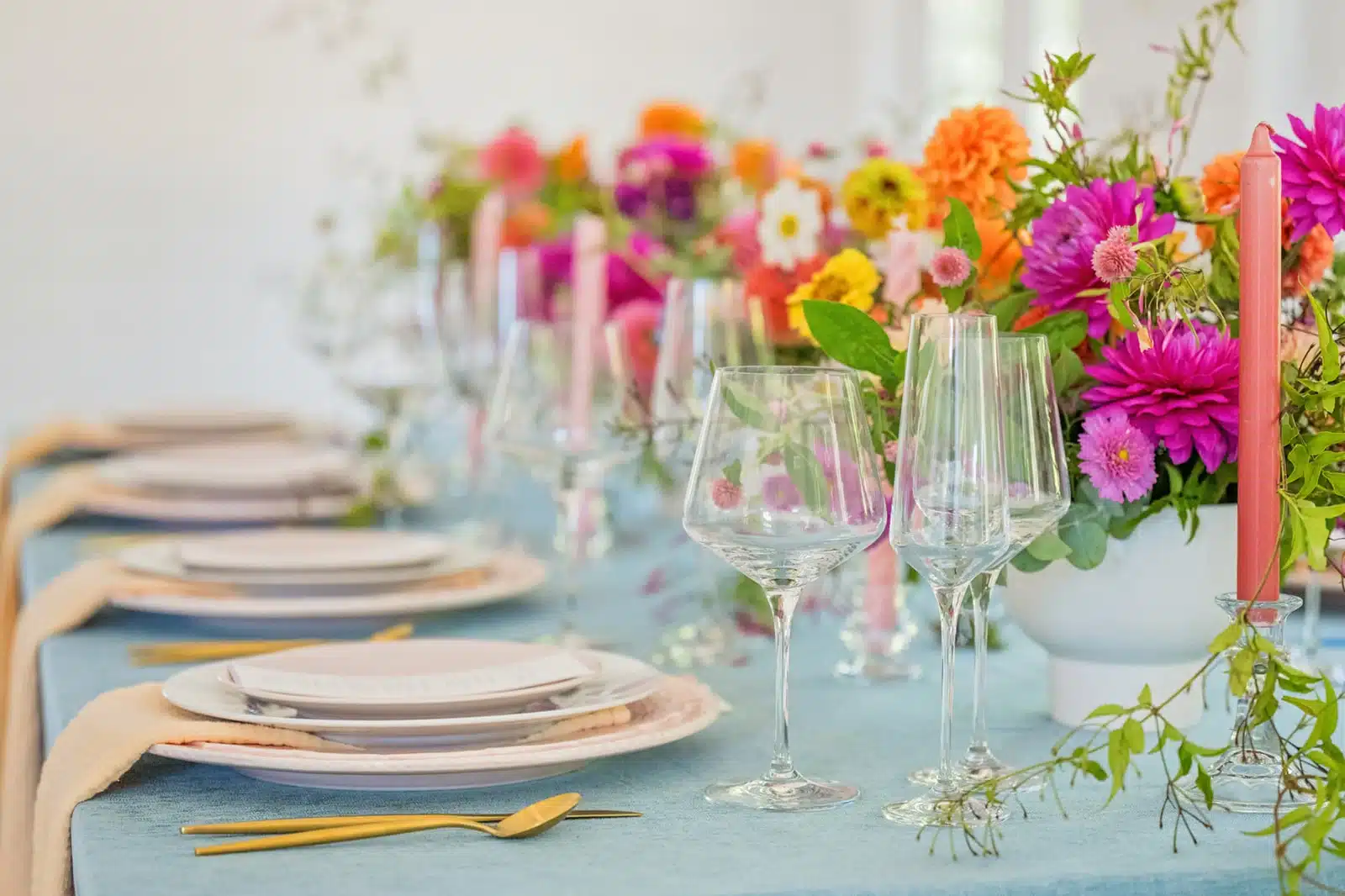 Wedding table decor, light blue tablecloth and colorful bright flowers and candles.