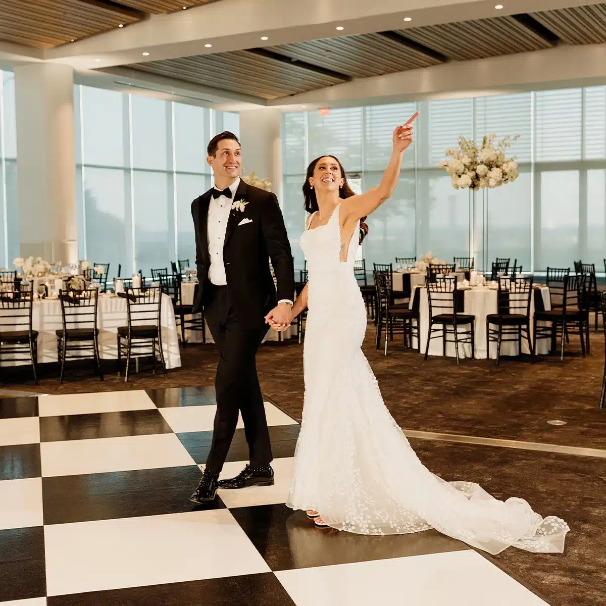 Bride and groom make grand entrance at wedding reception at Discovery World on top of black and white checkered dance floor.