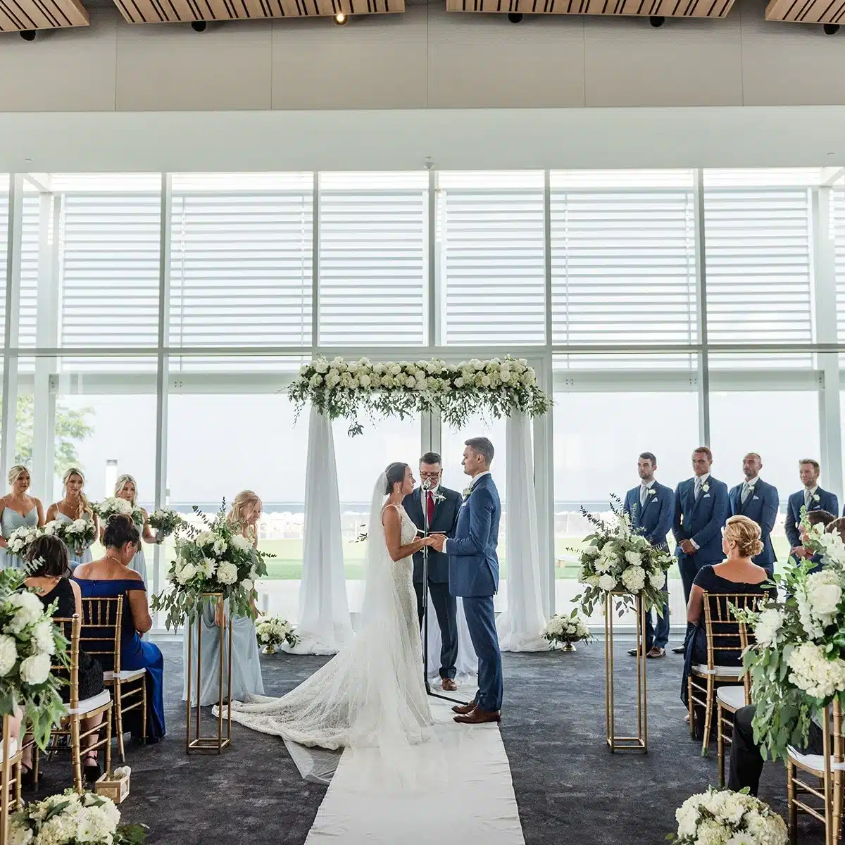 Indoor wedding ceremony at Bartolottas Discovery World withi glass windows in the background.
