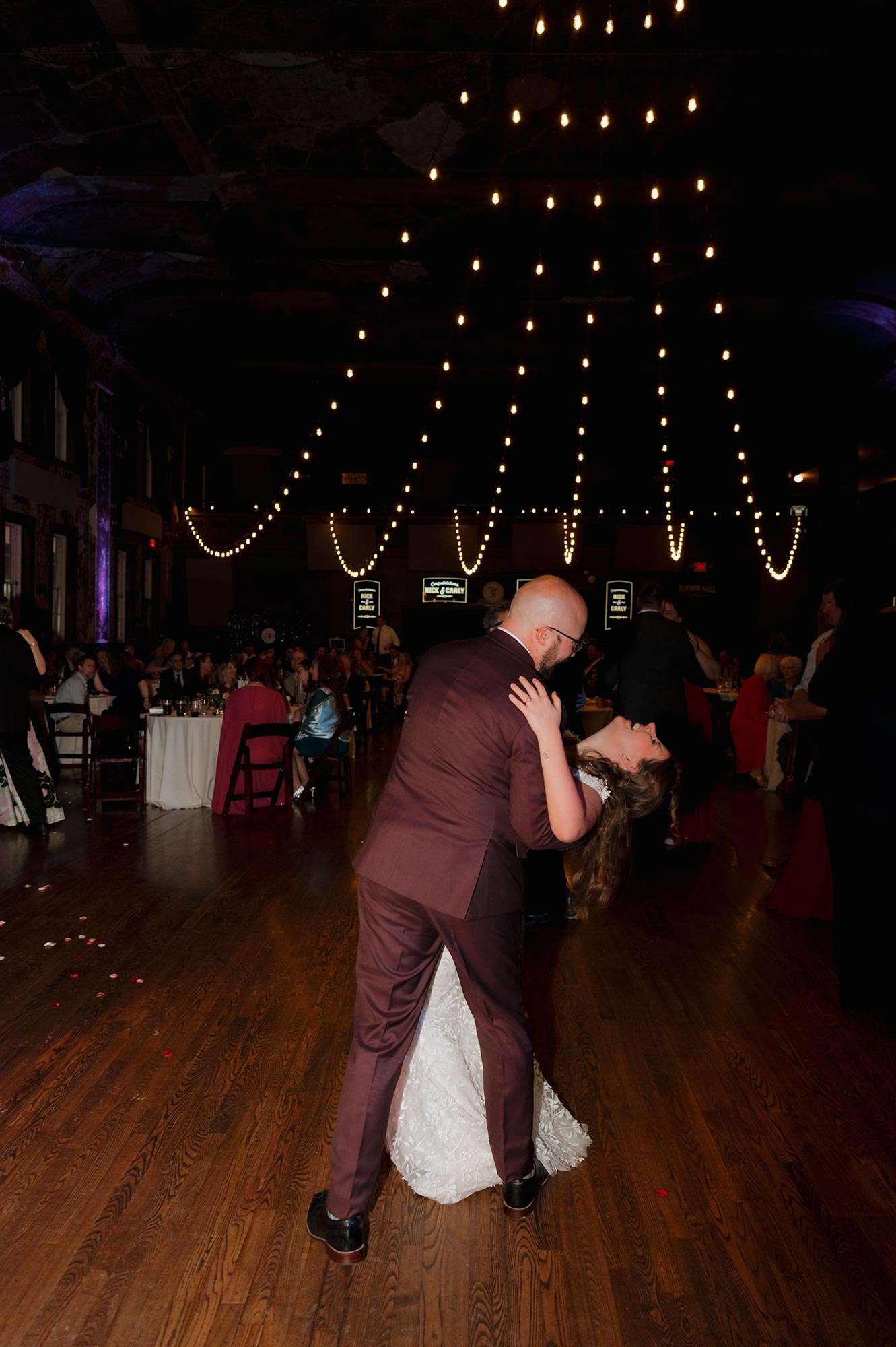 groom in maroon tux dipping bride on dance floor groom in maroon tux dipping bride on dance floor