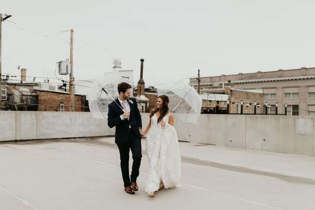 Bride and groom on rooftop location with clear umbrellas
