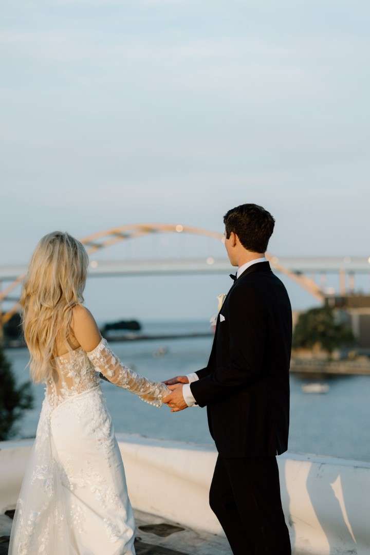 couple-holding-hands-looking-at-hoan-bridge Bride and groom hold hands as they look at the Hoan Bridge.