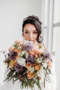 Bride peaking behind a colorful wedding bouquet. Bride peaking behind a colorful wedding bouquet.