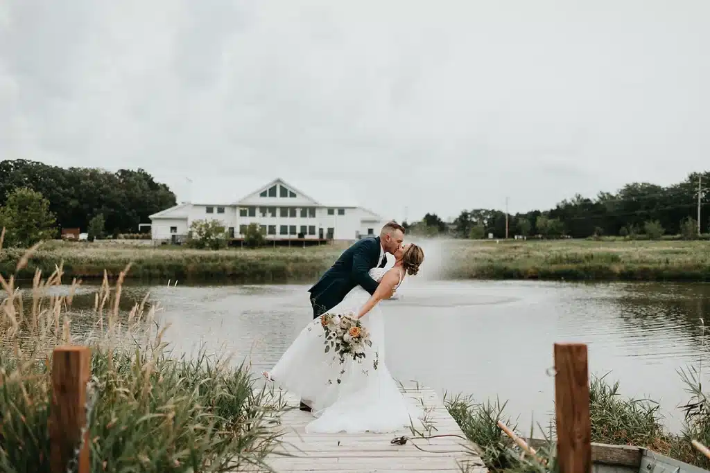 Lake Country Wisconsin Wedding Venue, fete of wales. Bride and groom kissing in front of lake.