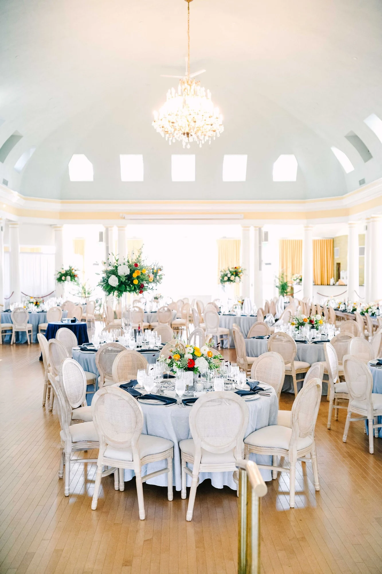 The Riviera Ballroom in Lake Geneva set up for blue and white wedding accented with custom chairs and colorful flower arrangements. The Riviera Ballroom in Lake Geneva set up for blue and white wedding accented with custom chairs and colorful flower arrangements.