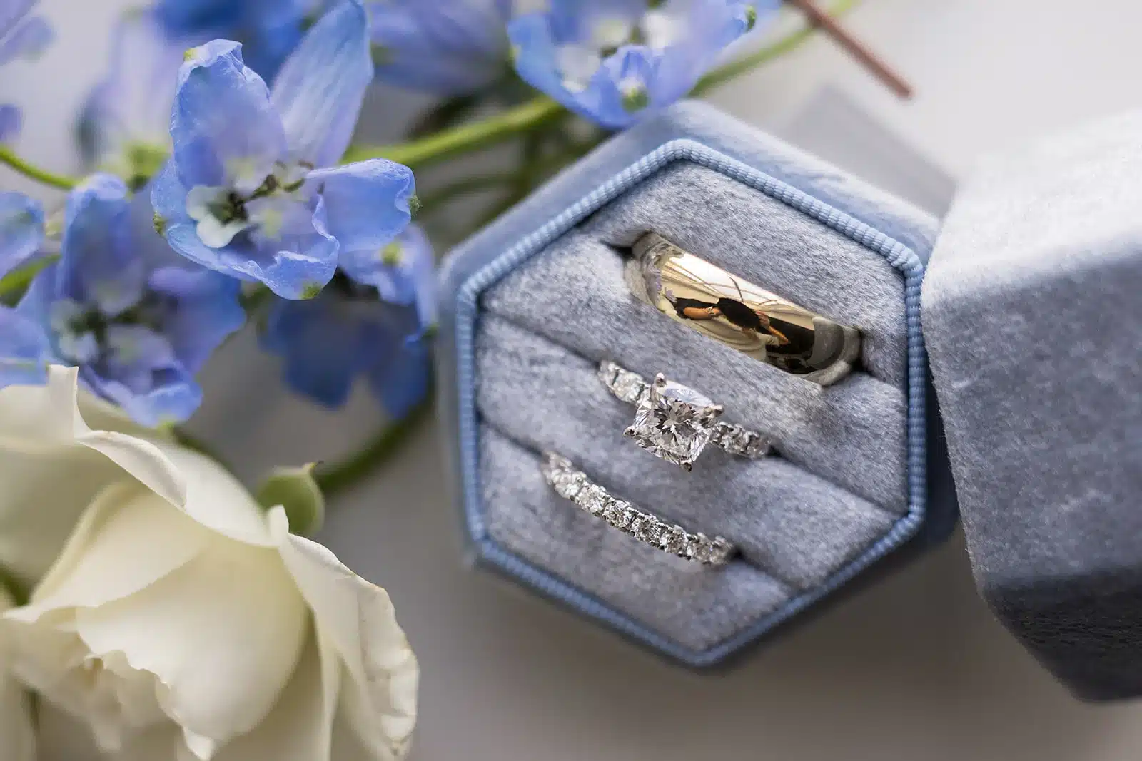 Gold mens wedding band, diamond engagement ring and eternity band set in blue ring box. Gold mens wedding band, diamond engagement ring and eternity band set in blue ring box.