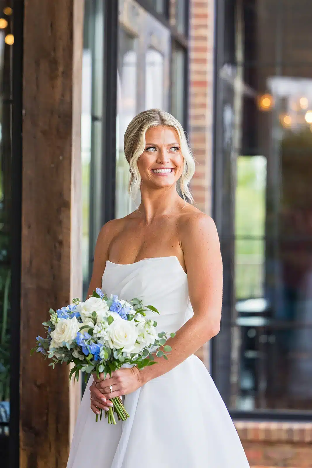 Bride wearing a strapless a-line wedding gown, with a white and blue wedding bouquet by Reflections of You at The Delafield Hotel. Bride wearing a strapless a-line wedding gown, with a white and blue wedding bouquet by Reflections of You at The Delafield Hotel.