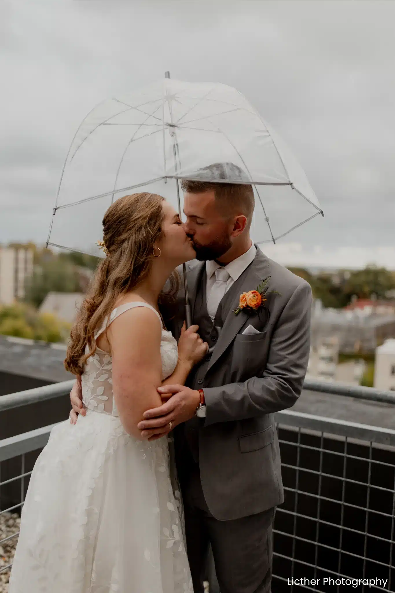 Wedding couple kissing under clear umbrella as it rains, Saz’s Hospitality. Wedding couple kissing under clear umbrella as it rains, Saz's Hospitality.