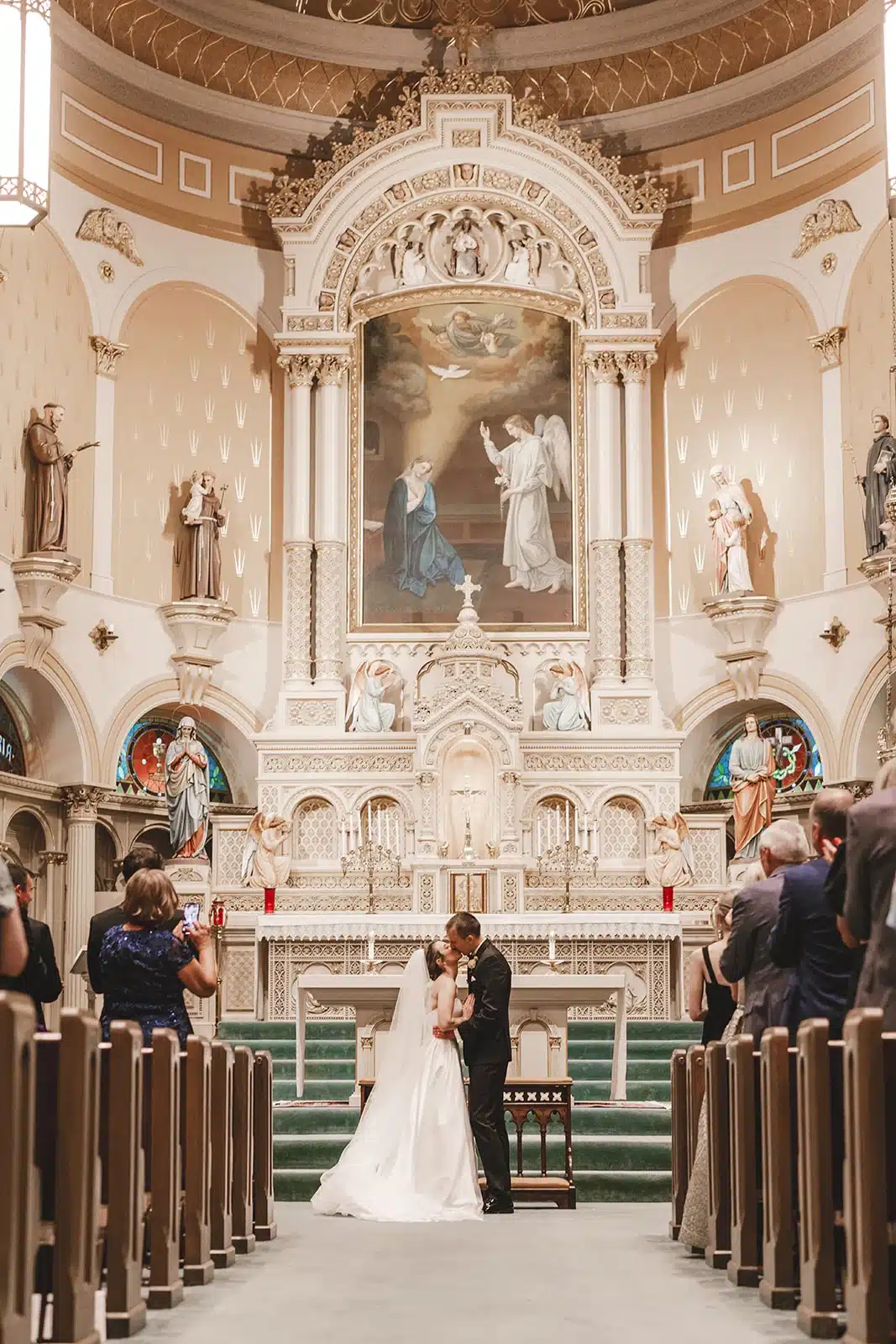 Bride and groom have first kiss at their wedding ceremony at Old Historic Saint Mary Church in Milwaukee, WI. Bride and groom have first kiss at their wedding ceremony at Old Historic Saint Mary Church in Milwaukee, WI.