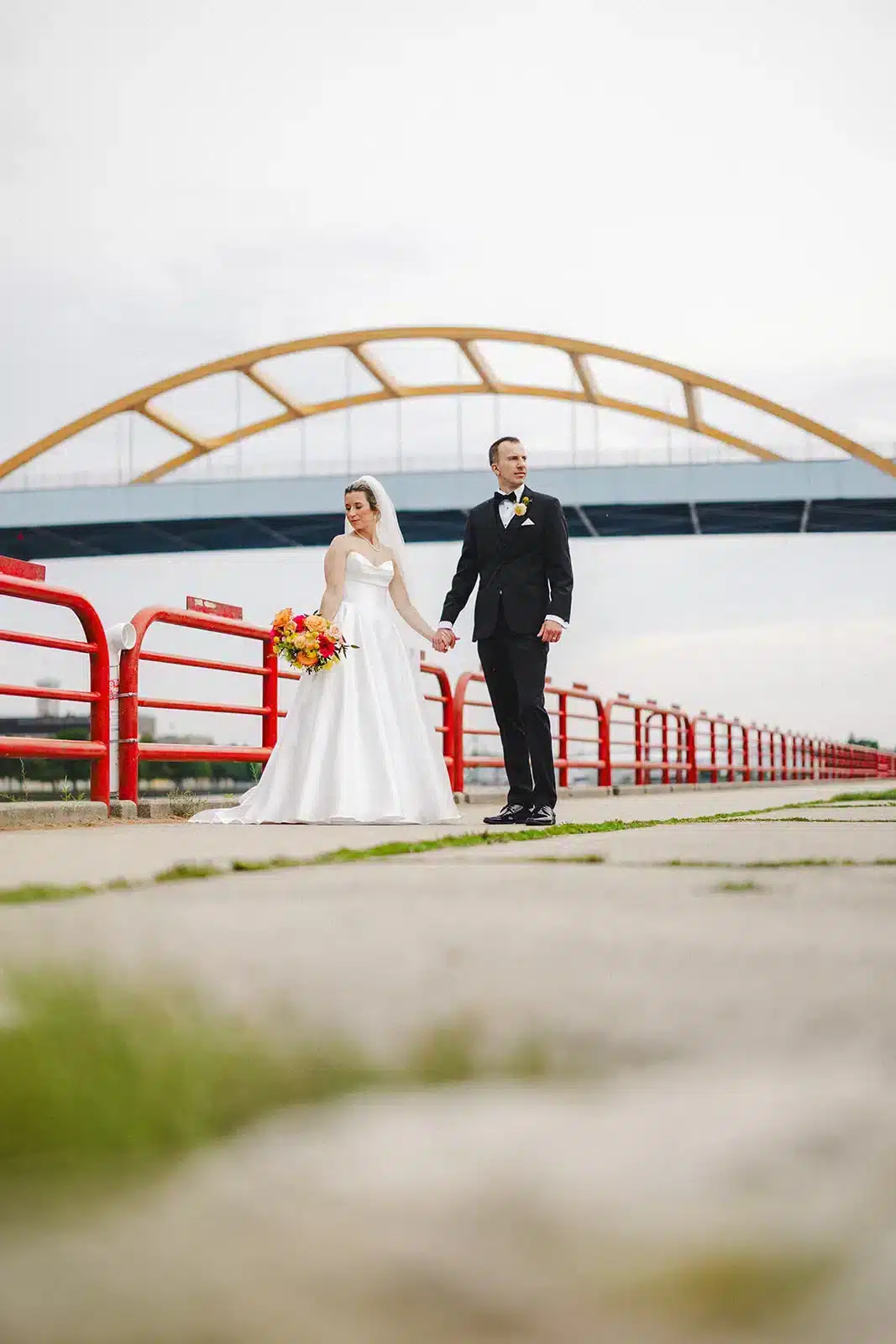 Bride and groom on Milwaukee’s riverfront with Hoan Bridge in the background. Bride and groom on Milwaukee's riverfront with Hoan Bridge in the background.