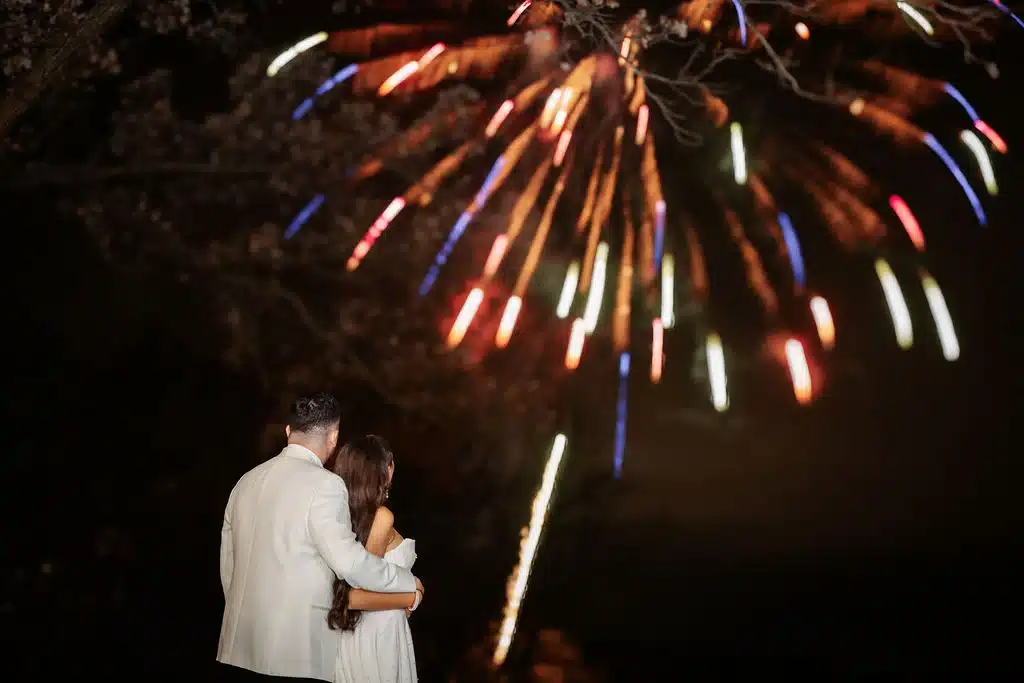 Bride and groom watch on as firework show is displayed for their guests. Bride and groom watch on as firework show is displayed for their guests.