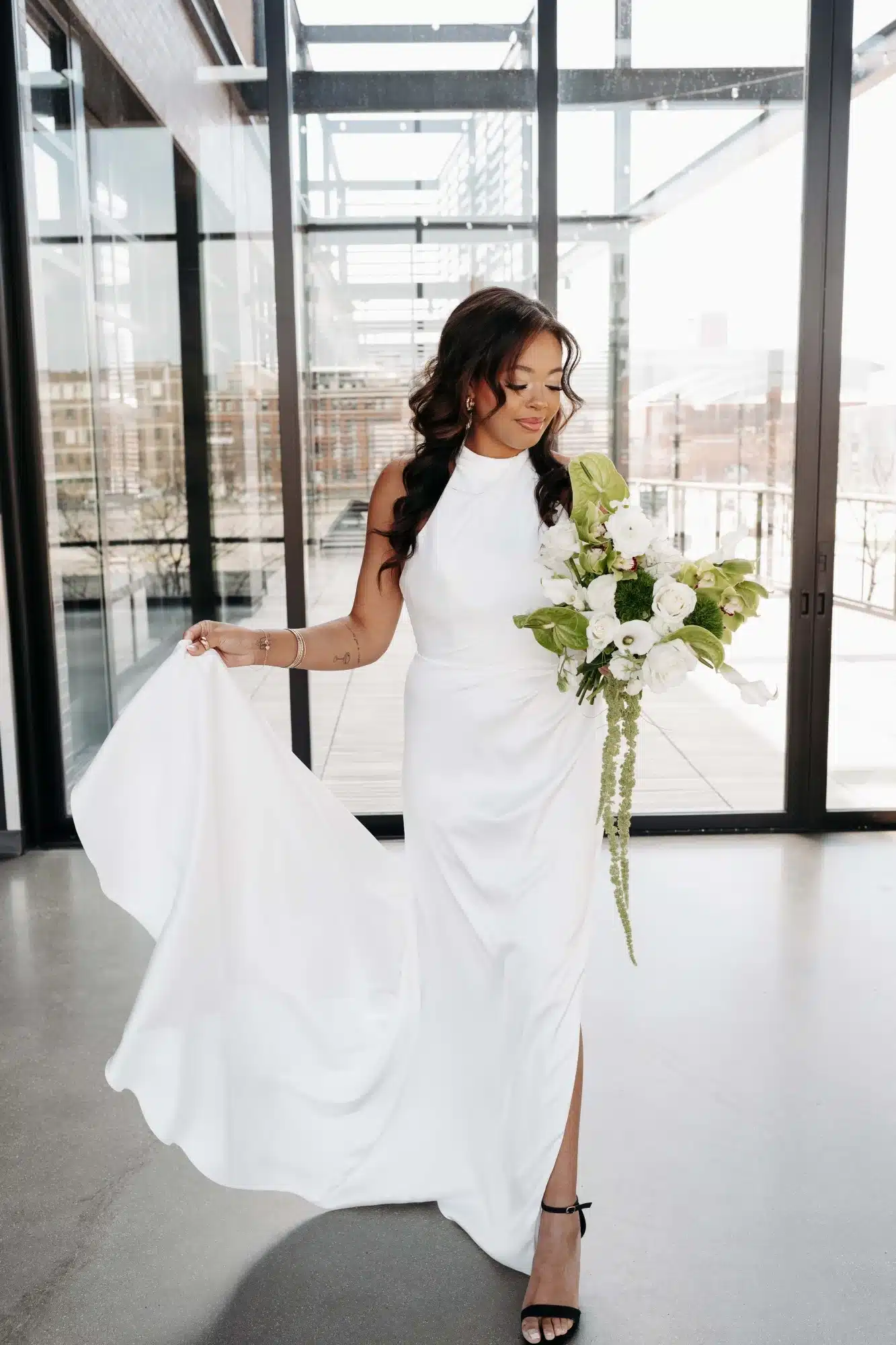 Bride walking with white halter gown, greenery bouquet and black strappy heels. Bride walking with white halter gown, greenery bouquet and black strappy heels.