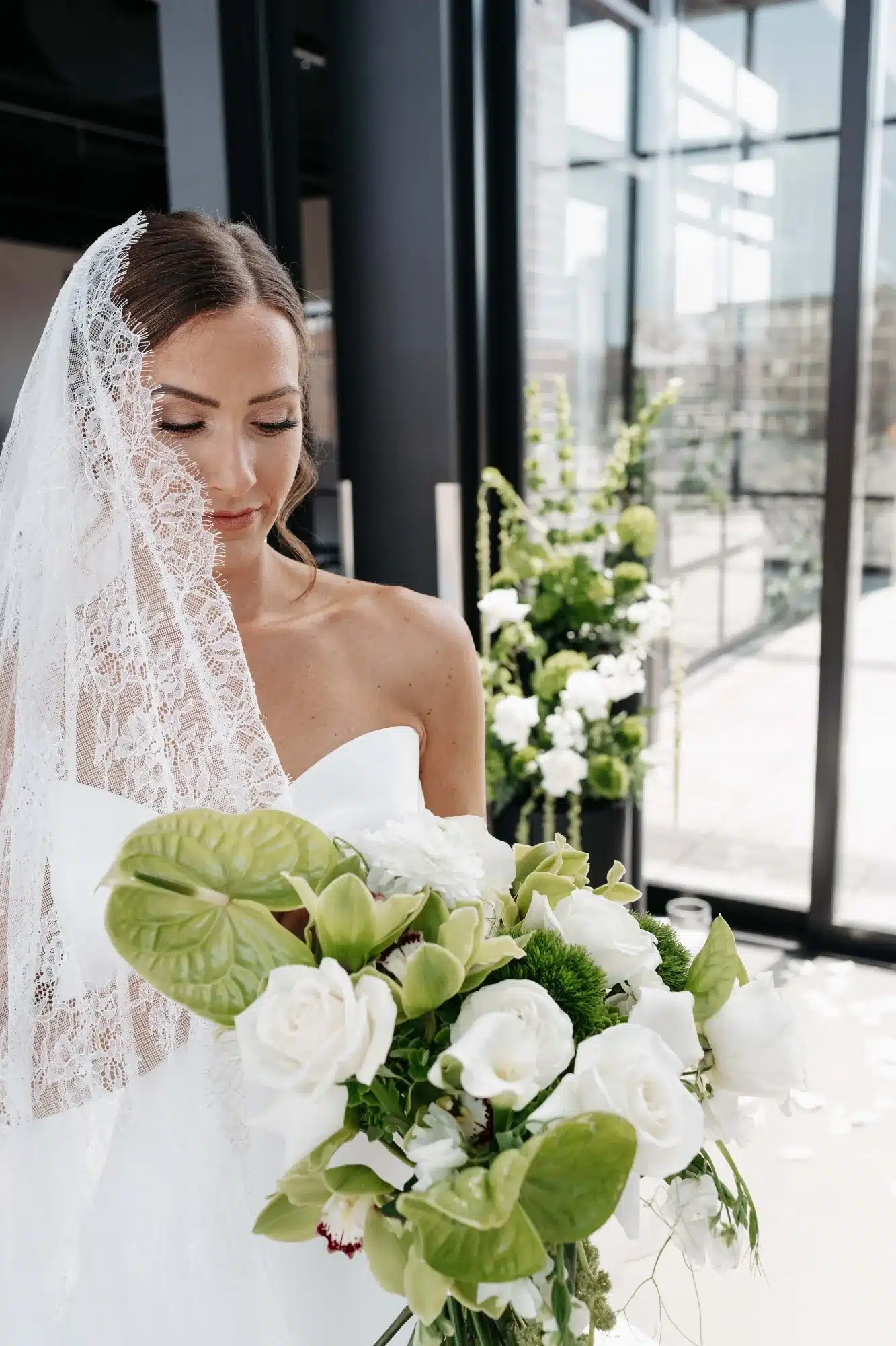 Bride looking at bridal bouquet as her veil sweeps across her face. Bride looking at bridal bouquet as her veil sweeps across her face.