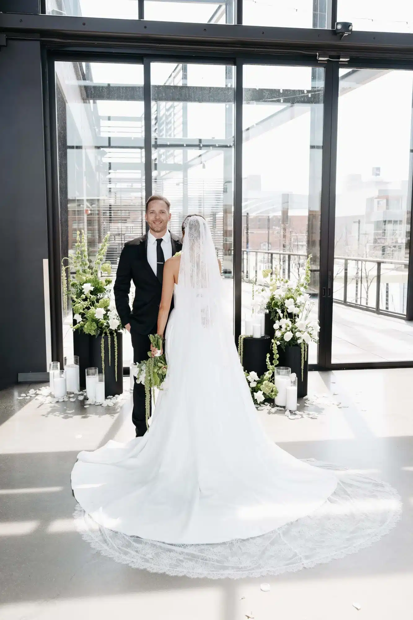 Groom looking towards camera as bride faces the other way and shows off her cathedral veil. Groom looking towards camera as bride faces the other way and shows off her cathedral veil.
