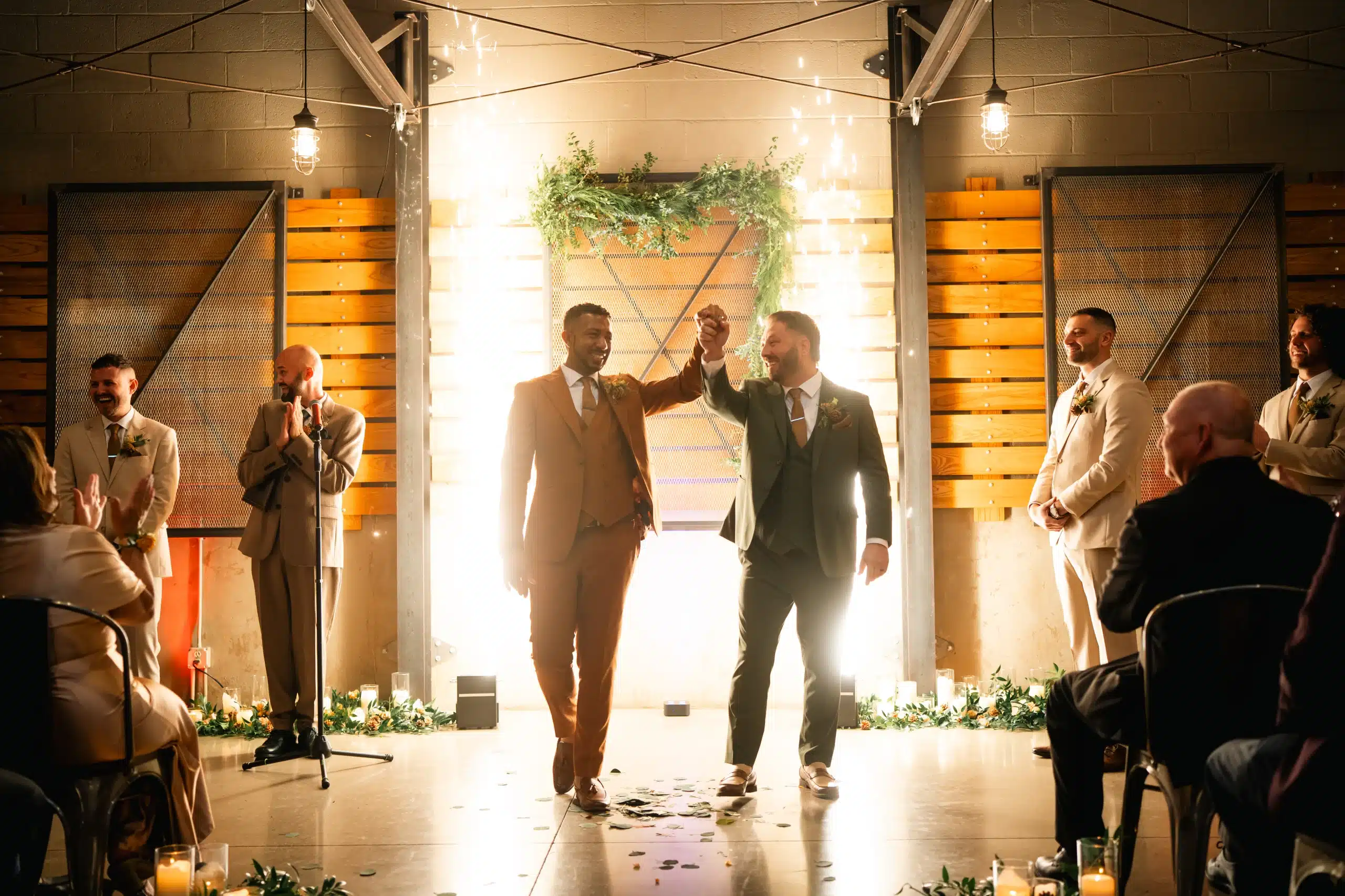 Grooms get married inside of South Second Milwaukee with Cold Sparks going off in the background.