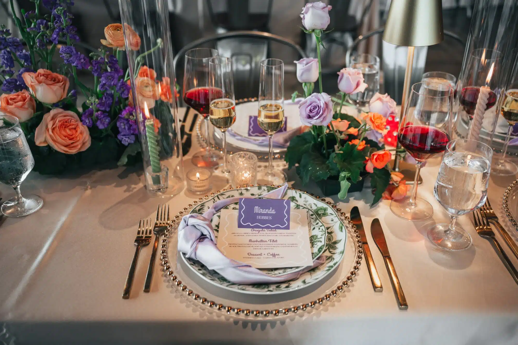 Tablescape by Celebrait by Kait with colorful flowers, gold beaded chargers, gold flatware, green floral vintage plates and purple accents. Tablescape by Celebrait by Kait with colorful flowers, gold beaded chargers, gold flatware, green floral vintage plates and purple accents.