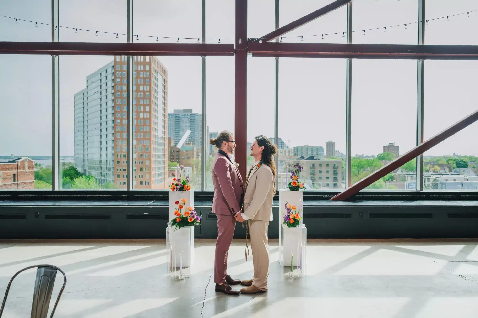 Grooms look into each others eyes at wedding ceremony of white pillars and colorful flower arrangements. Grooms look into each others eyes at wedding ceremony of white pillars and colorful flower arrangements.