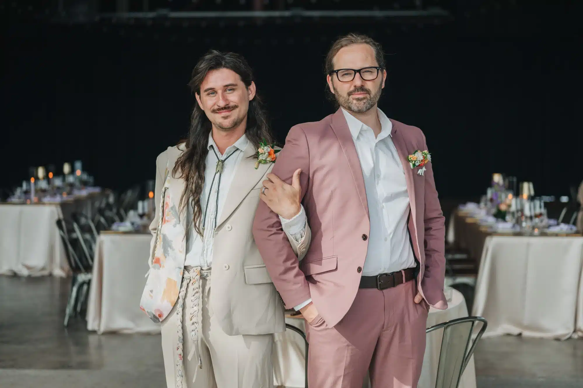 Grooms pose together with a colorful styled shoot in the background. Grooms pose together with a colorful styled shoot in the background.