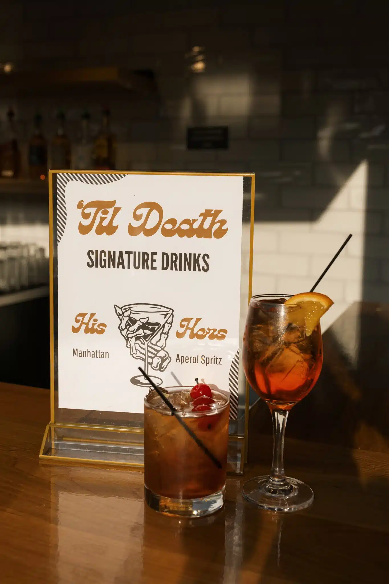 Til' Death signature drink sign of a Manhattan and Aperol Spritz.