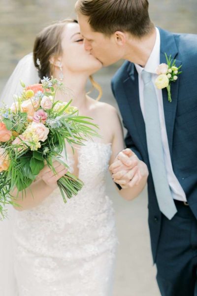 Bride holding bouquet kisses groom.