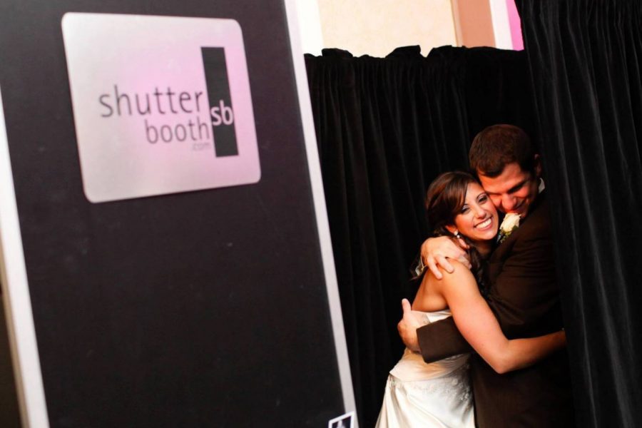Bride and groom hugging in from of Shutter Booth at their wedding
