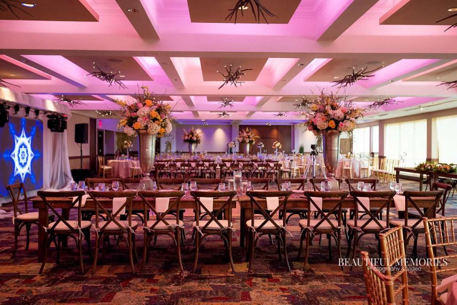 Elegant wedding reception with wooden cross-back chairs and tall floral centerpieces by Ambrosia Events