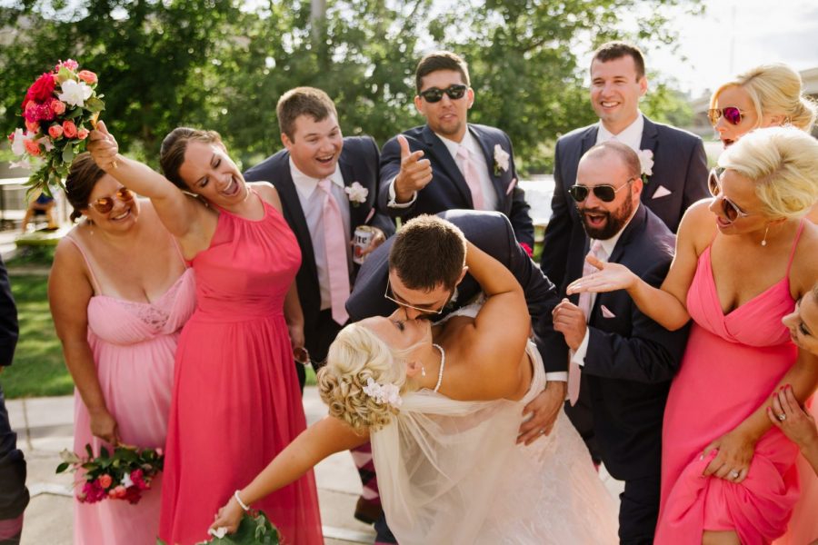 Groom kisses his bride while wedding party cheers them on