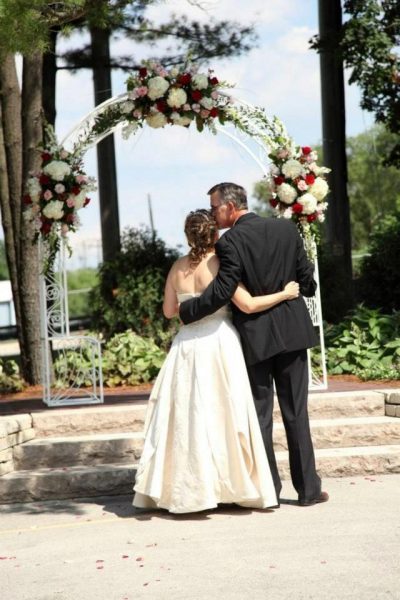 Floral drenched arch at the outdoor ceremony area at the Red Circle Inn with wedding couple looking on
