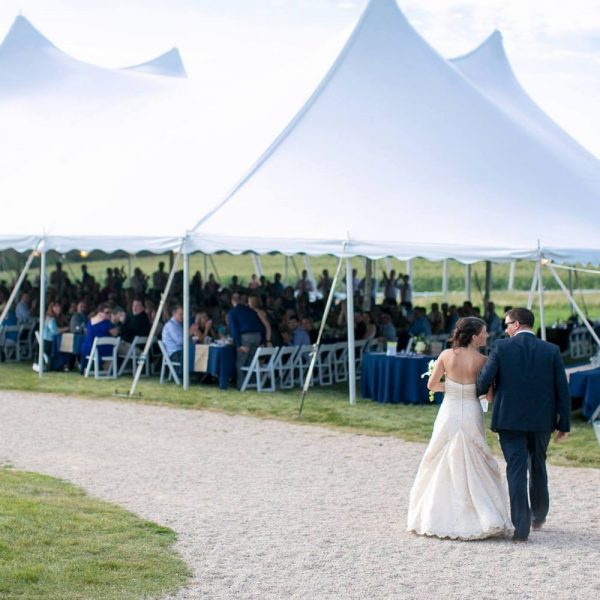 Bride and groom walk to tent rented from Brookfield Party Rental