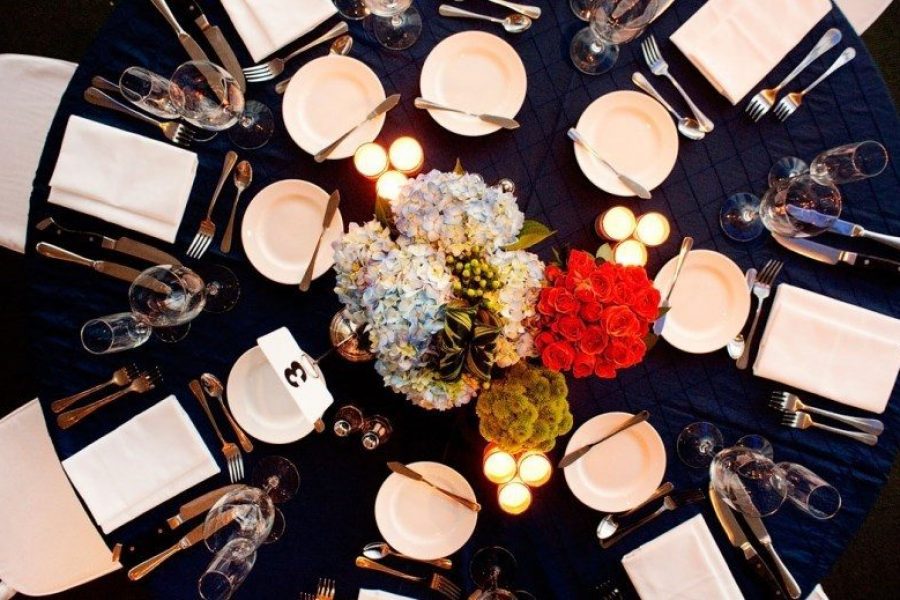 Aerial image of an elegant tabletop with black tablecloth, white napkins and large floral centerpiece