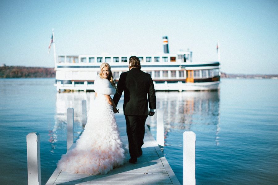 Bride and groom on pier overlooking Lake Geneva and boat