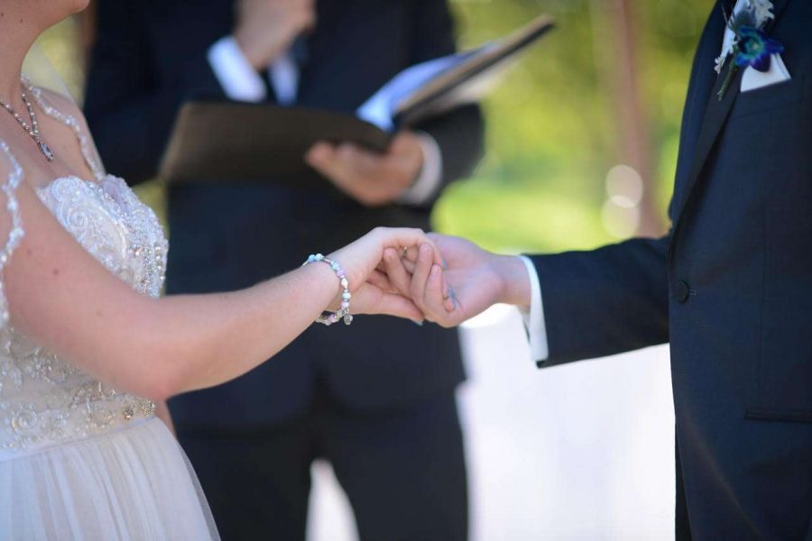 Officiant performing ceremony with couple holding hands at Davians outdoor wedding ceremony
