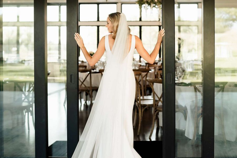 Bride poses at doors of the Carriage House at the Club at Lac La Belle