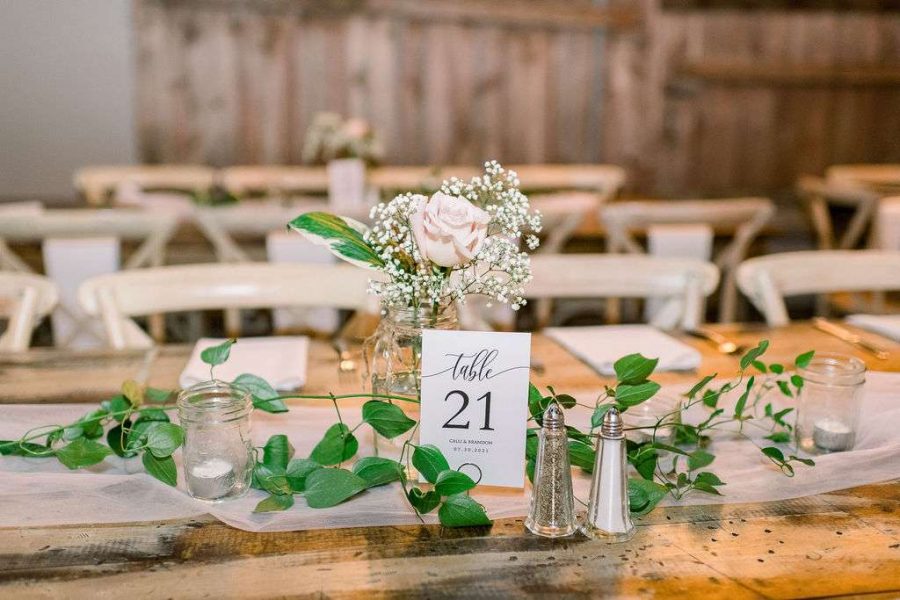 Simple floral wedding table decor for reception with greenery and single rose. Floral done by Bank of Flowers in Wisconsin.