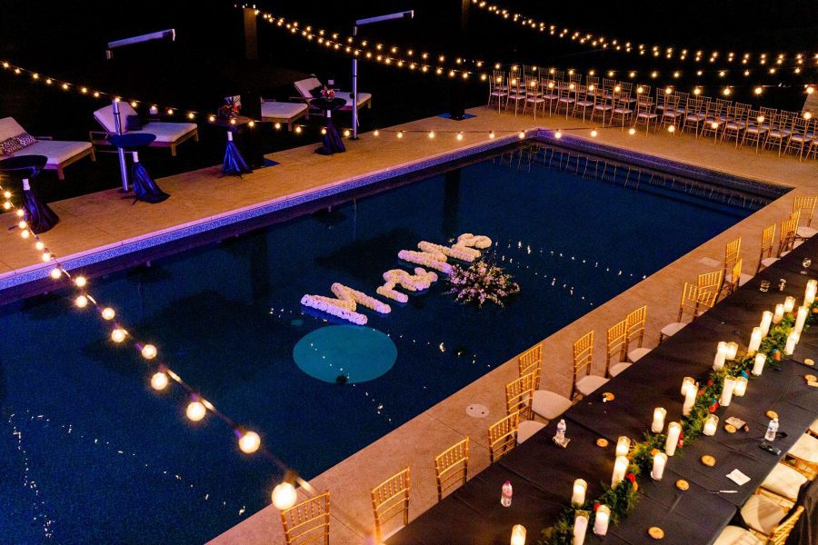 Overhead nighttime view of pool with floating flowers by Ambrosia Events