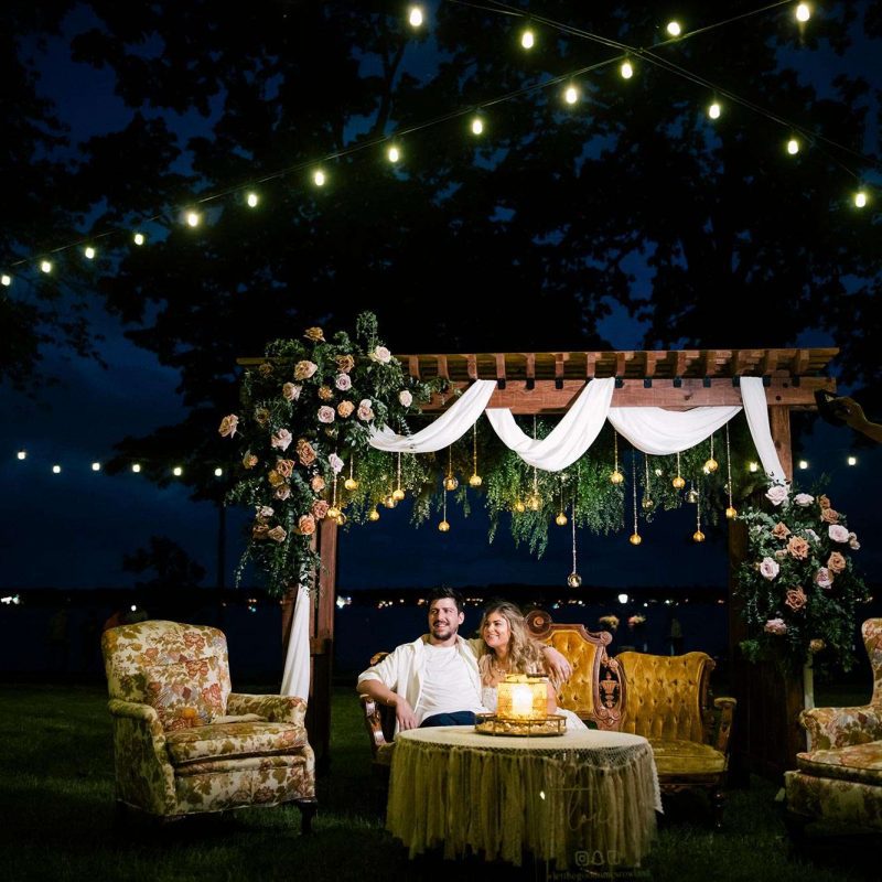 Brooke and Nick unwind on the antique couch under the wedding arch