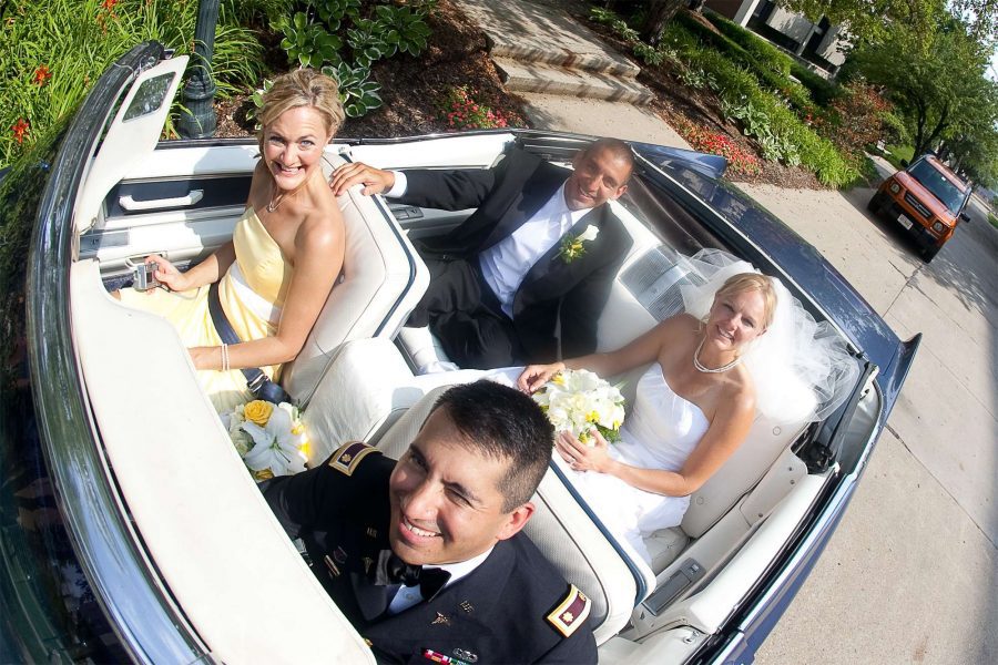 Newlywed and wedding party in convertible