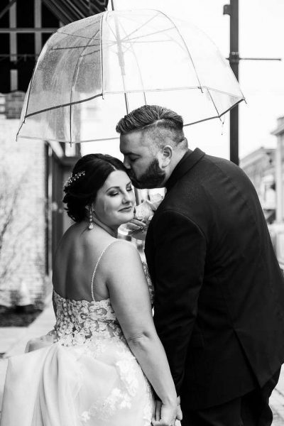 Groom kisses bride under umbrella